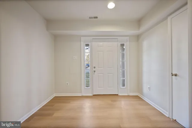 a view of a hallway with entryway and hall with wooden floor