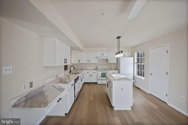 a kitchen with a sink a stove a refrigerator and white cabinets