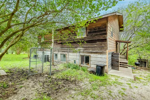 a view of a backyard with wooden fence and a large tree