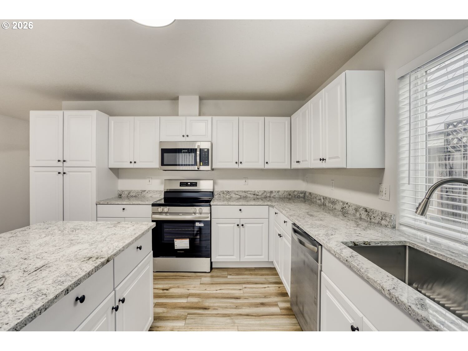 7642 Southwest 205th Terrace Beaverton, OR 97007 - Photo 13 of 28 a kitchen with granite countertop a sink stainless steel appliances and white cabinets