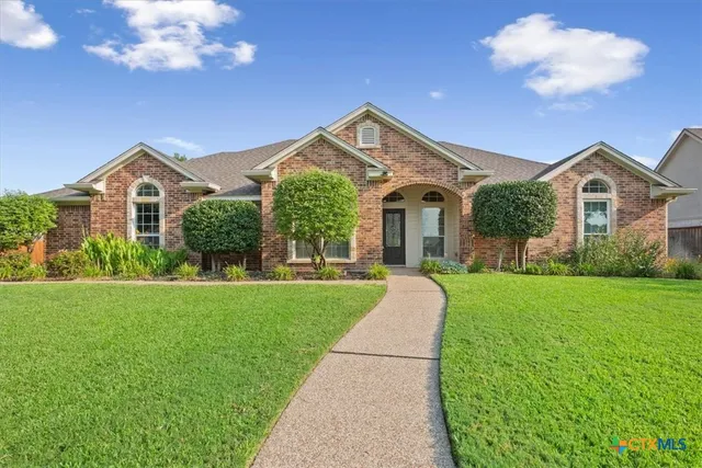 a front view of a house with a yard and potted plants