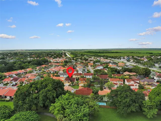 an aerial view of residential houses with outdoor space and trees