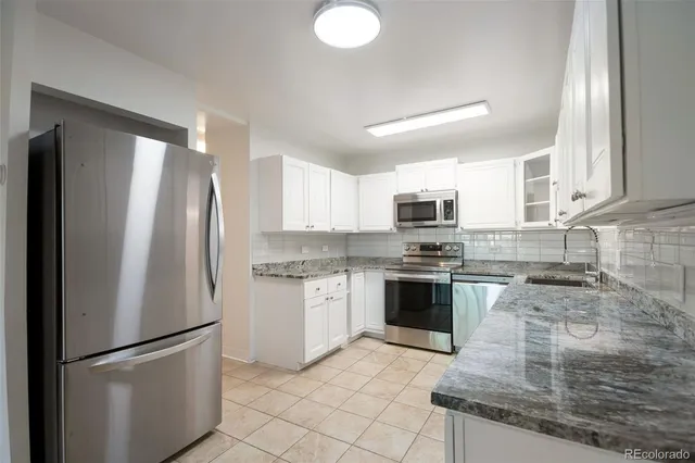 a kitchen with granite countertop a refrigerator stove top oven and sink