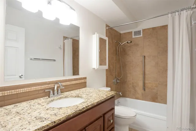 a bathroom with a granite countertop sink toilet and shower