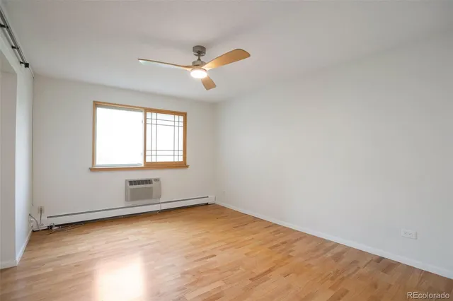 an empty room with wooden floor cabinet and windows