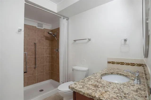 a bathroom with a granite countertop sink a toilet and shower