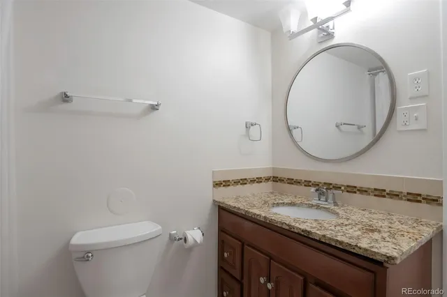 a bathroom with a granite countertop sink a mirror and toilet