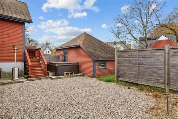 a backyard of a house with large tree and wooden fence