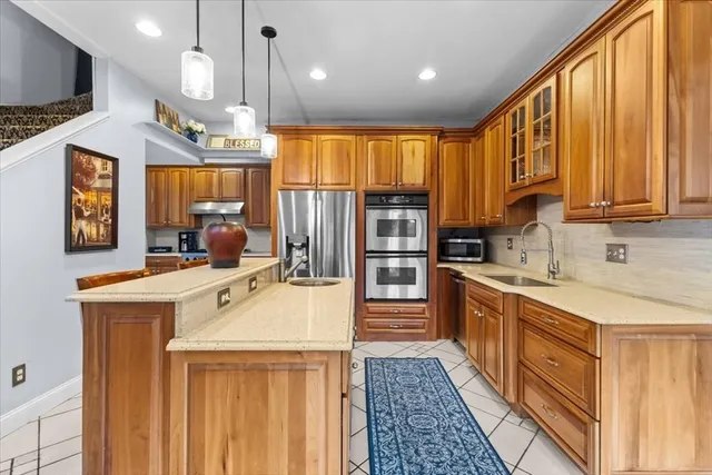 a kitchen with kitchen island granite countertop a sink appliances cabinets and a counter top space