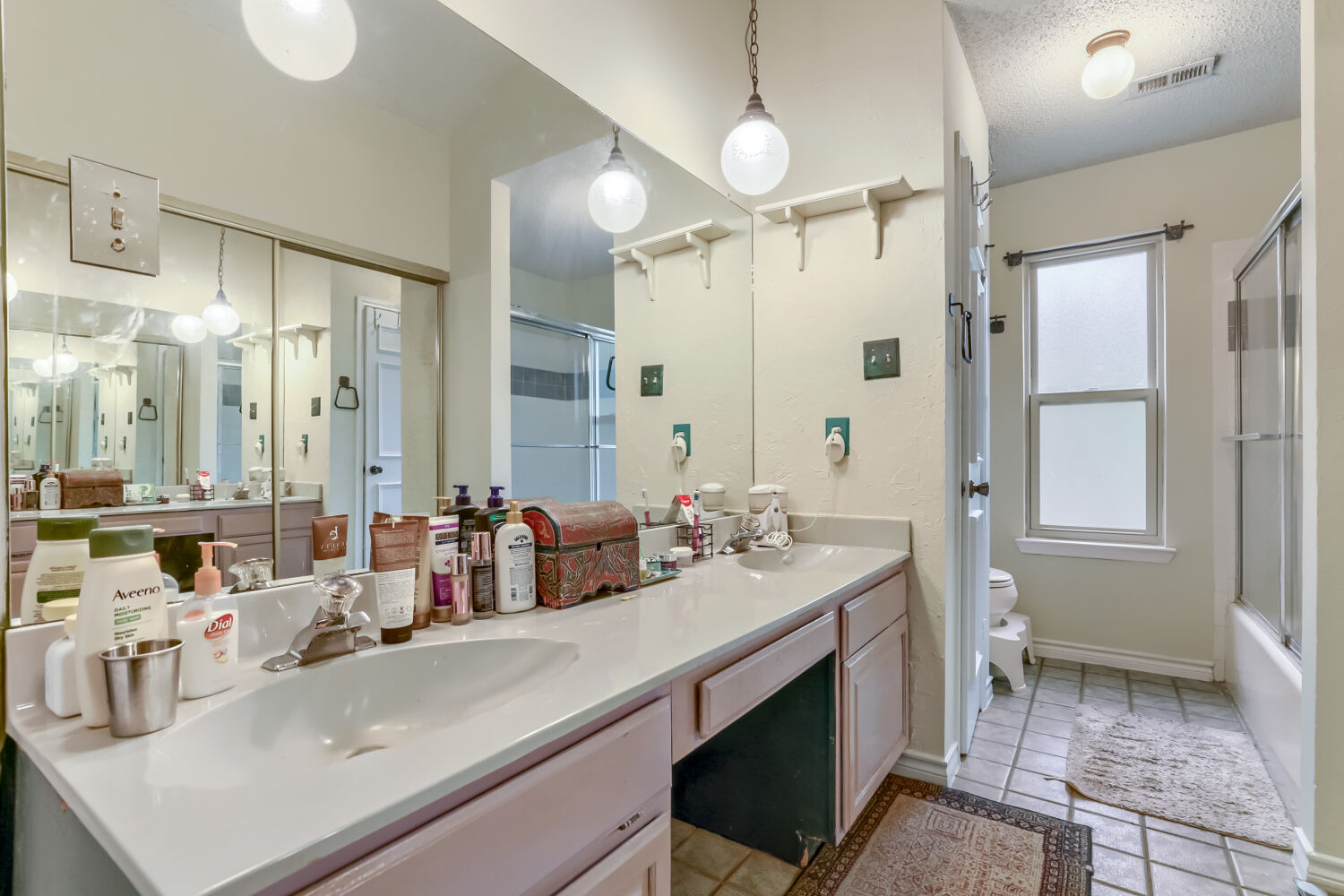 13129 New Boston Bend Austin, TX 78729 - Photo 13 of 26 Full bath with double vanity, combined bath / shower with glass door, a textured ceiling, and light tile patterned flooring