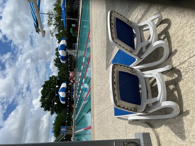 13129 New Boston Bend Austin, TX 78729 - Photo 25 of 26 The property features an extensive outdoor swimming pool with lane markers, accompanied by several blue and white striped umbrellas and lounge chairs