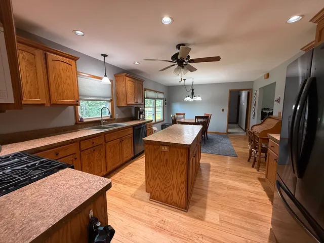a kitchen with stainless steel appliances granite countertop wooden cabinets a sink dishwasher a stove and a refrigerator