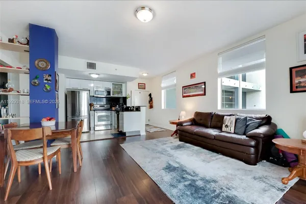 a living room with furniture and kitchen view with wooden floor