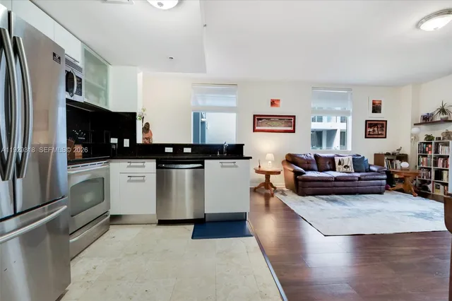 a kitchen with stainless steel appliances a refrigerator a stove a sink dishwasher and white cabinets with wooden floor