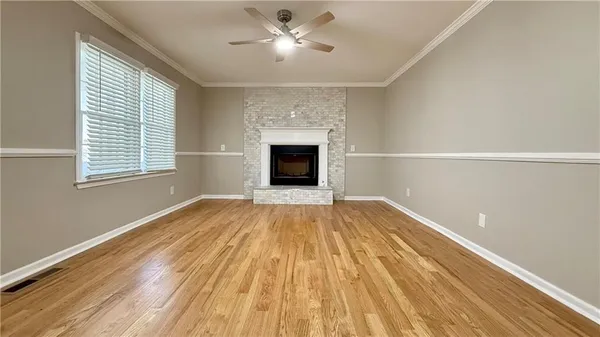 a view of empty room with wooden floor and fireplace