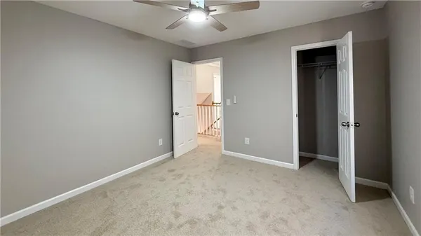 an empty room with closet and a ceiling fan