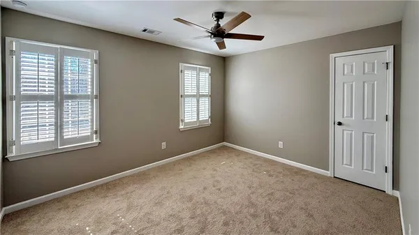an empty room with windows and ceiling fan