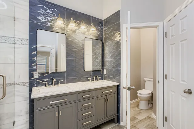 a bathroom with a double vanity sink mirror and toilet