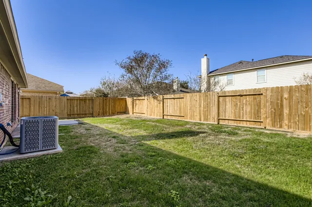 a view of a backyard with large trees and wooden fence