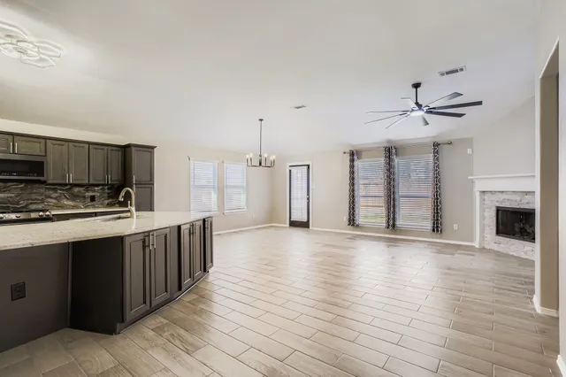 a kitchen with stainless steel appliances a stove top oven a sink cabinets and a wooden floor