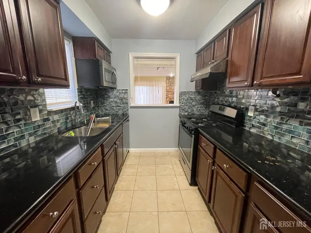 a kitchen with stainless steel appliances granite countertop a stove a sink and a microwave
