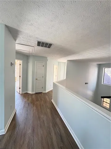 a view of hallway with window and wooden floor