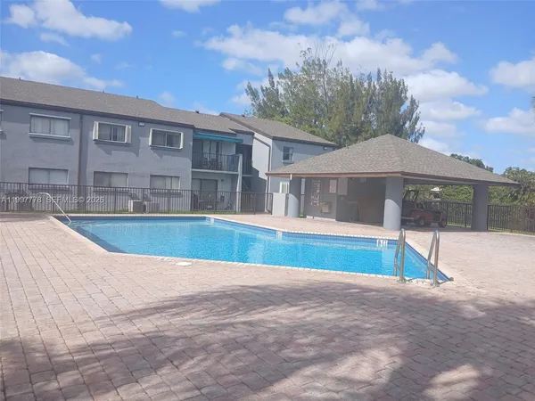 a view of pool with brick walls plants and large tree