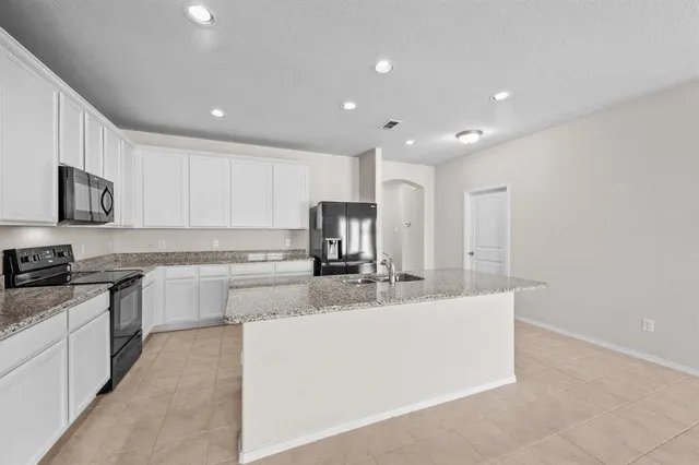 a large kitchen with stainless steel appliances granite countertop a sink a stove and a refrigerator