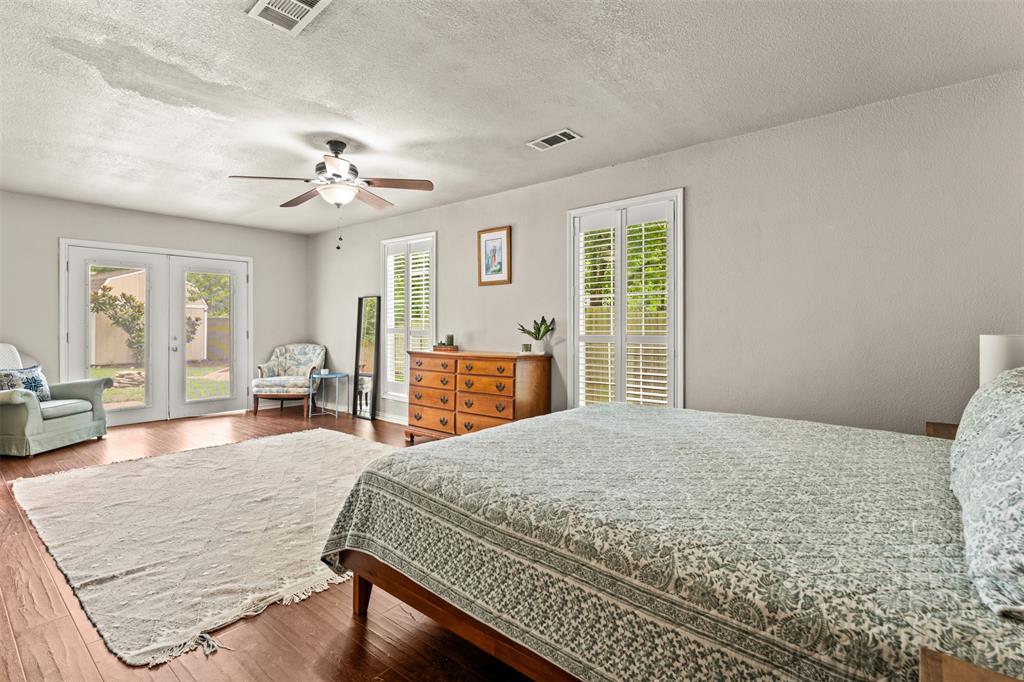 3116 Alexander Avenue Waco, TX 76708 - Photo 18 of 40 a bedroom with a large bed a chandelier and windows
