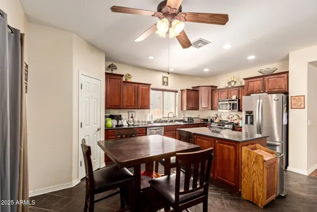 a kitchen with stainless steel appliances a dining table chairs refrigerator and cabinets