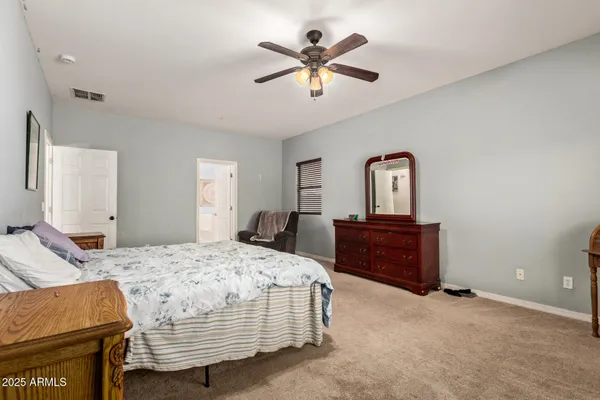 a bedroom with a bed and a dresser with wooden floor