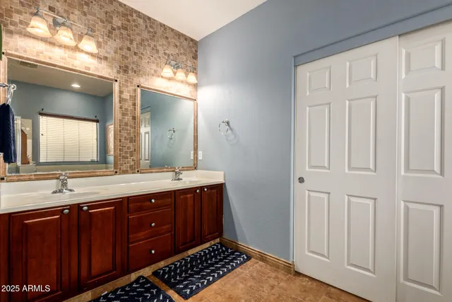 a spacious bathroom with a granite countertop double vanity sink a mirror and