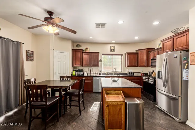 a kitchen with stainless steel appliances granite countertop a refrigerator a sink a stove a dining table and chairs