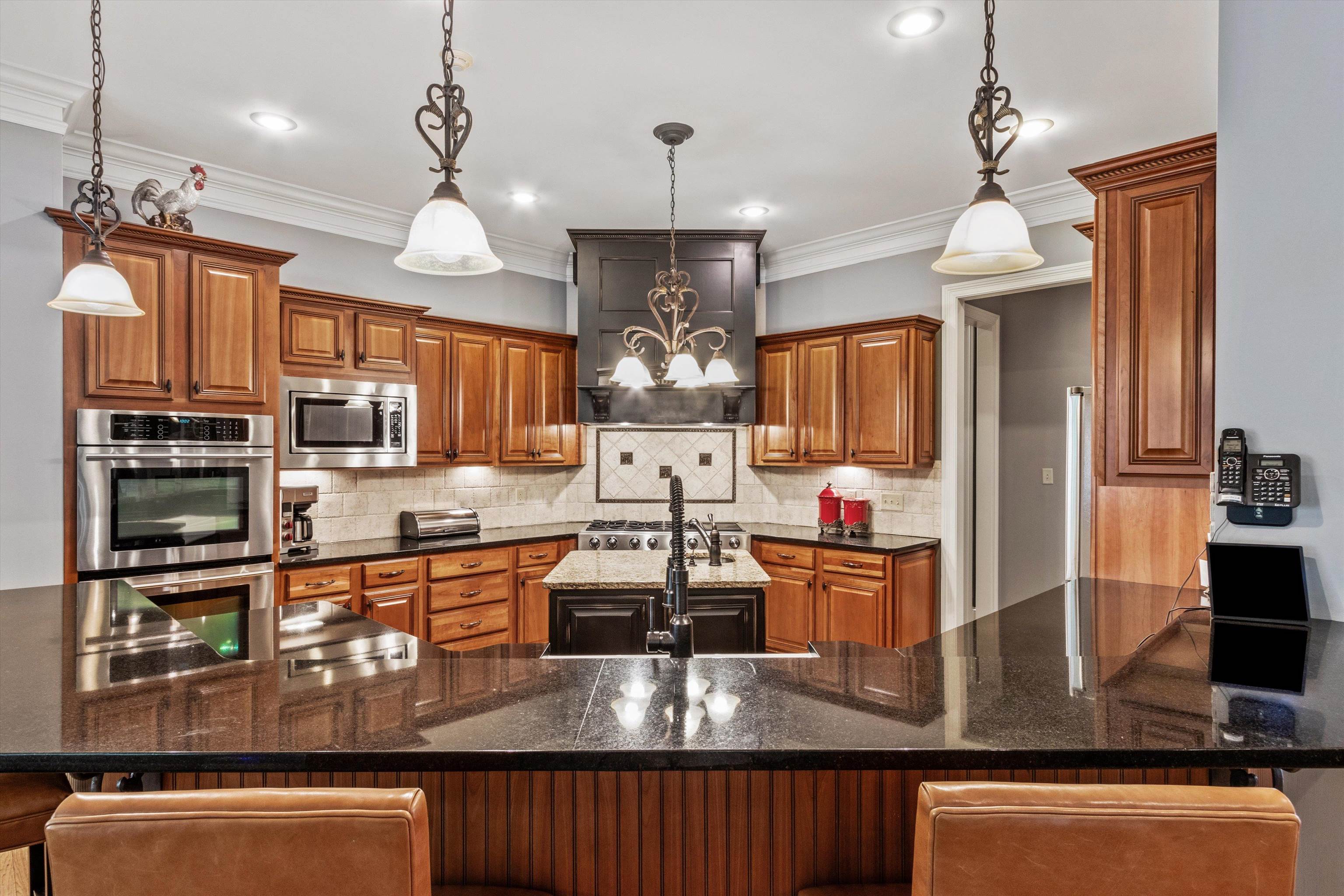 150 Ridgecrest Drive Arlington, TN 38002 - Photo 13 of 40 Kitchen featuring wood cabinetry, stainless steel appliances, dark countertops, a central island with sink, and decorative pendant lighting