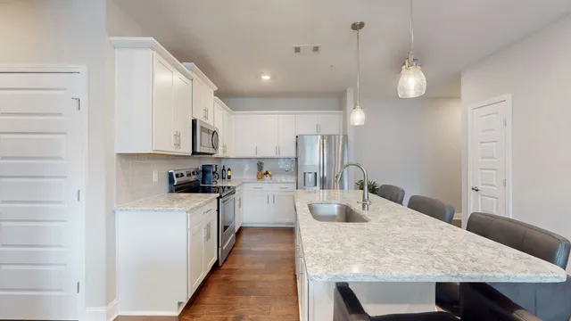 a kitchen with stainless steel appliances a dining table chairs and wooden floor