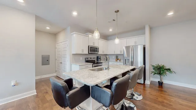 a open kitchen with stainless steel appliances granite countertop a stove a sink dishwasher a dining table and chairs with wooden floor