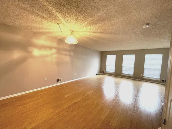 a view of an empty room with window and wooden floor