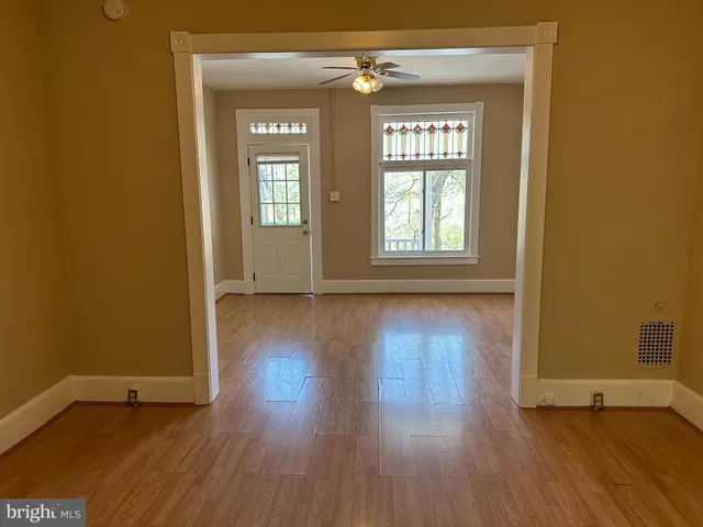 an empty room with wooden floor and windows