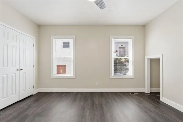 an empty room with wooden floor and windows