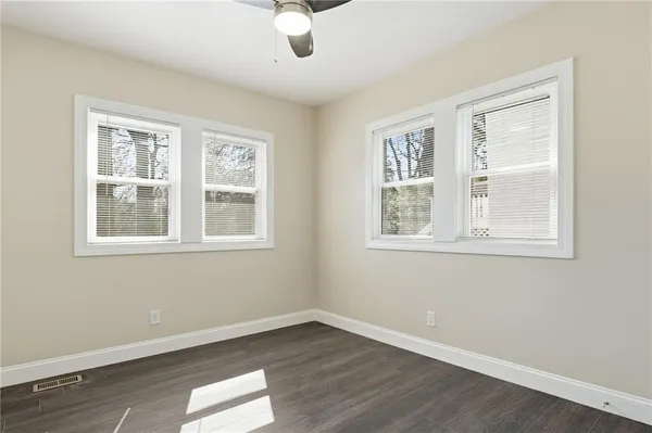 a view of an empty room with wooden floor and windows