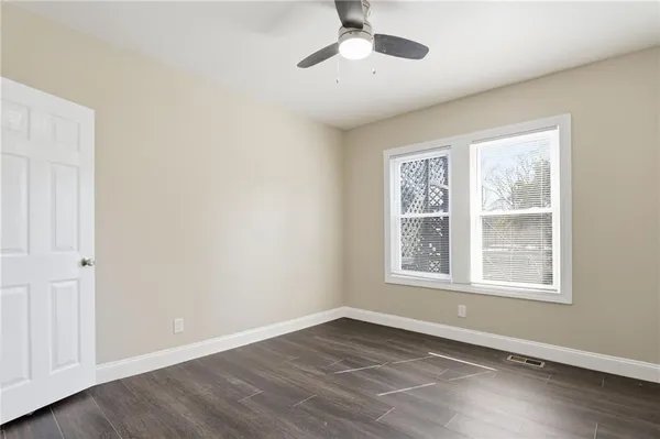 a view of an empty room with a window and wooden floor