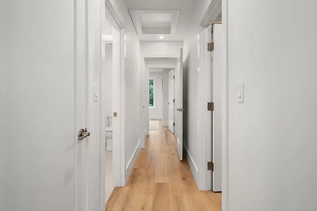 a view of a hallway with wooden floor and a bathroom