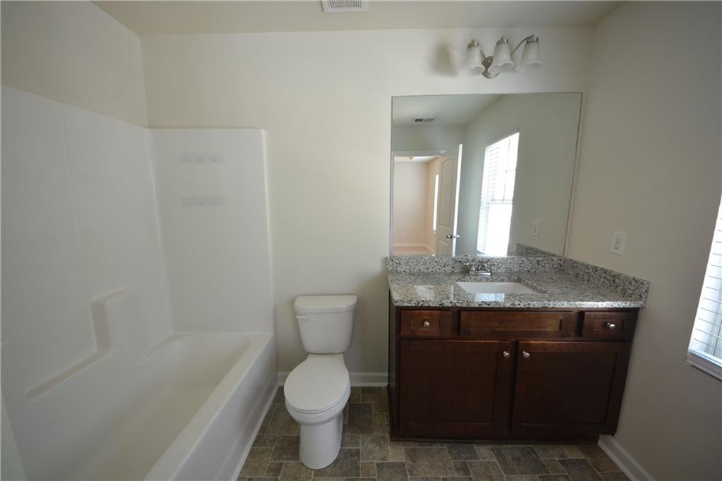 5873 Taka Lane Lithonia, GA 30038 - Photo 20 of 26 a bathroom with a granite countertop toilet a sink and a mirror