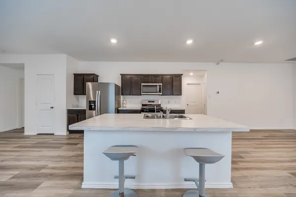 a view of a kitchen with kitchen island a sink stainless steel appliances and cabinets