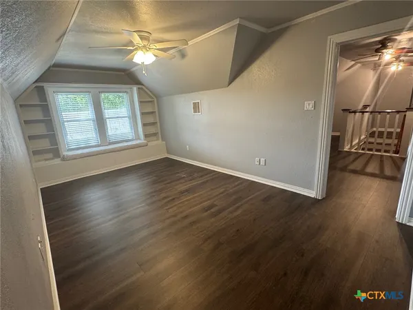 an empty room with wooden floor fan and windows