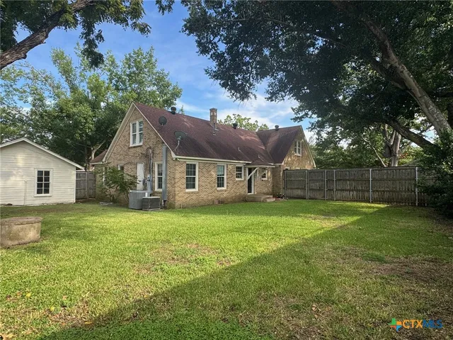 a house that is sitting in the grass with tress in the background