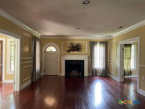 an empty room with wooden floor fireplace and windows