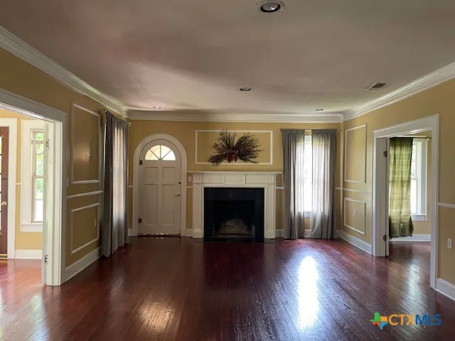 an empty room with wooden floor fireplace and windows
