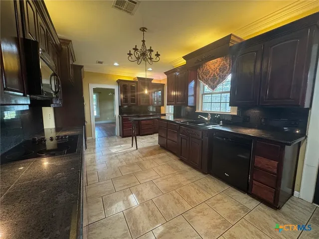 a kitchen with stainless steel appliances granite countertop a stove a sink and a microwave