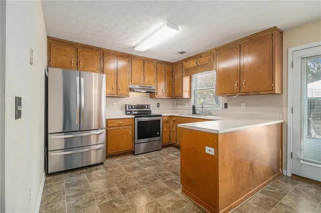 a kitchen with granite countertop stainless steel appliances a refrigerator and a sink